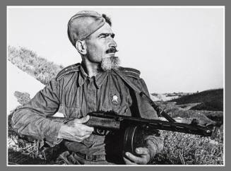 Bearded soldier and machine gun