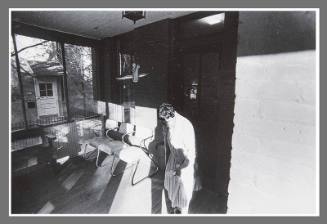 Untitled (Woman and chairs on front porch)
