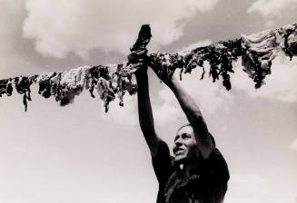 Spanish-American woman hanging up meat to dry.  Chamisal, New Mexico